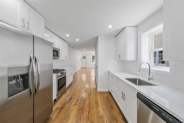 kitchen featuring backsplash, stainless steel appliances, sink, hardwood / wood-style floors, and white cabinetry