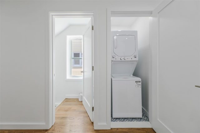 laundry room with light hardwood / wood-style flooring and stacked washer and clothes dryer