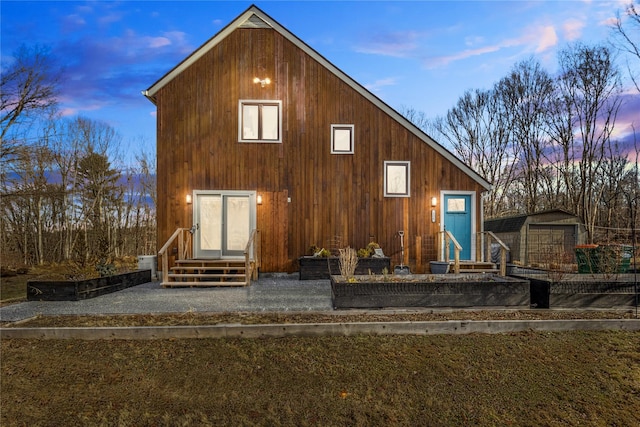 back of house at dusk with entry steps and an outdoor structure