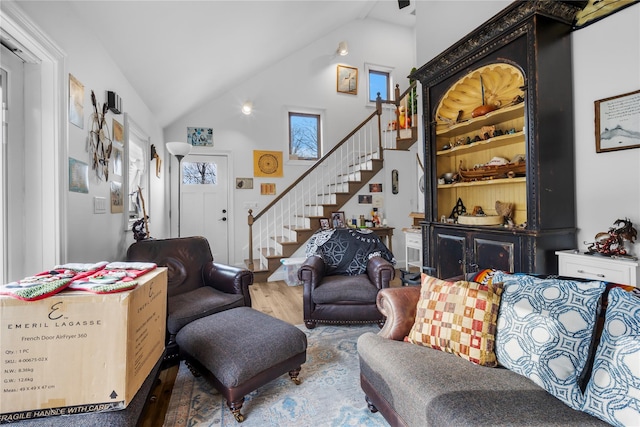 living room featuring stairs, high vaulted ceiling, and wood finished floors