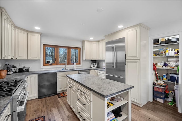 kitchen with premium appliances, a sink, light wood-type flooring, a center island, and open shelves