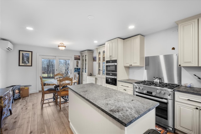 kitchen featuring stainless steel gas stove, dark countertops, a kitchen island, glass insert cabinets, and an AC wall unit