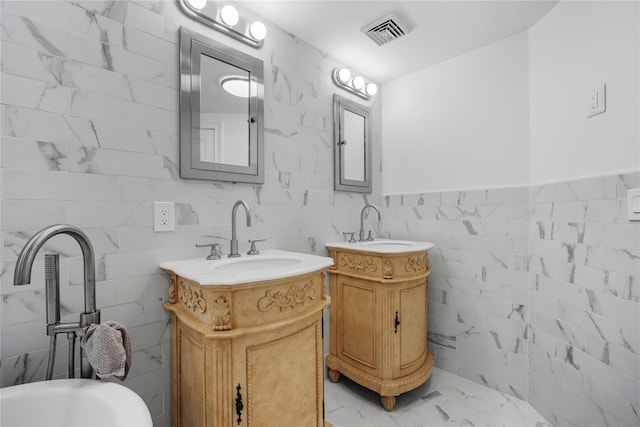 bathroom featuring marble finish floor, tile walls, visible vents, and a sink