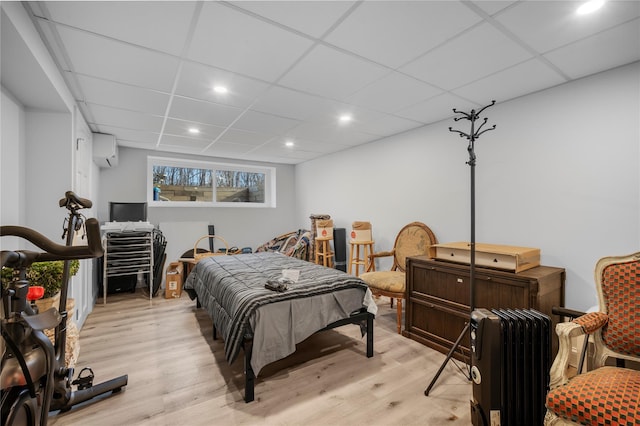 bedroom with recessed lighting, a wall mounted air conditioner, a drop ceiling, and light wood finished floors