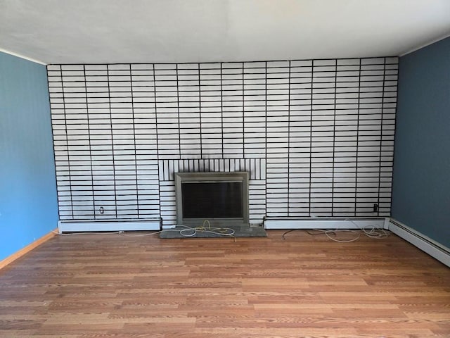 unfurnished living room featuring baseboard heating and wood-type flooring