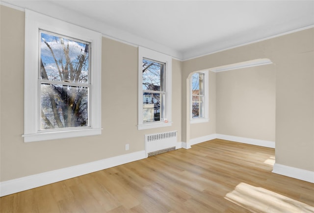 empty room with radiator, crown molding, and hardwood / wood-style floors