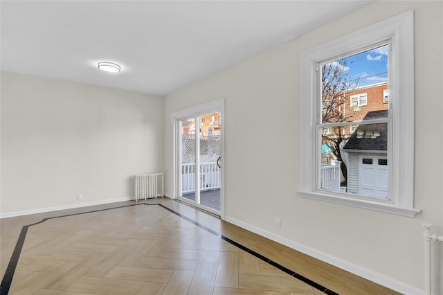 spare room featuring radiator and light parquet floors