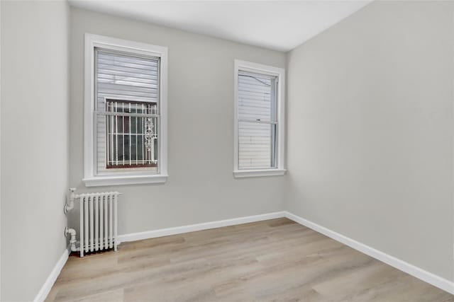 unfurnished room featuring radiator, plenty of natural light, and light hardwood / wood-style floors