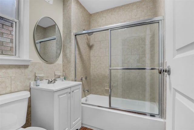 full bathroom with tasteful backsplash, combined bath / shower with glass door, toilet, vanity, and tile walls