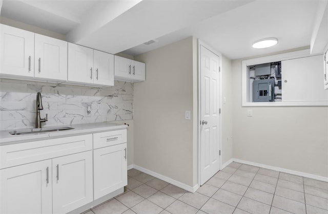 kitchen with white cabinets, decorative backsplash, light tile patterned flooring, and sink