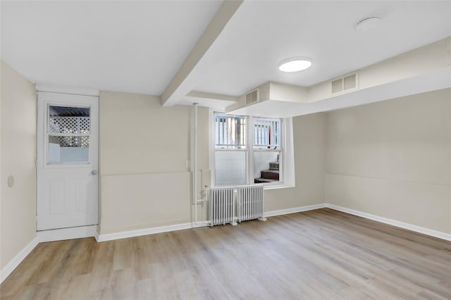 basement featuring light hardwood / wood-style flooring and radiator