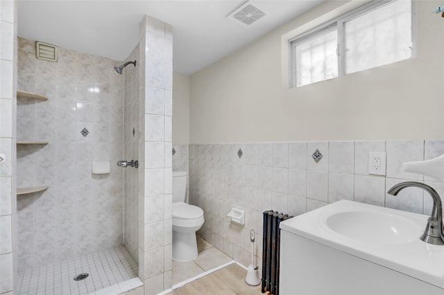 bathroom featuring tiled shower, radiator, tile walls, and toilet