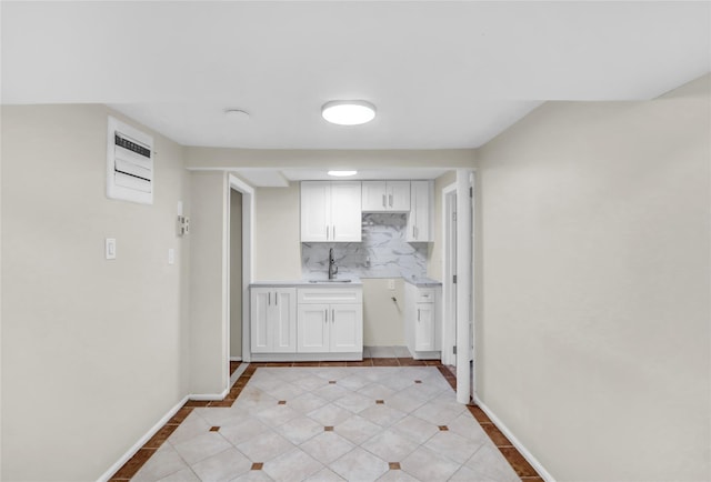 kitchen with tasteful backsplash, sink, white cabinets, and light tile patterned floors