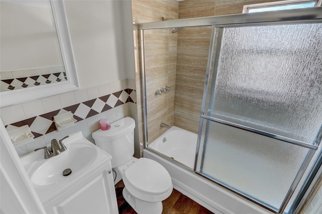 full bathroom featuring vanity, toilet, shower / bath combination with glass door, and tile walls