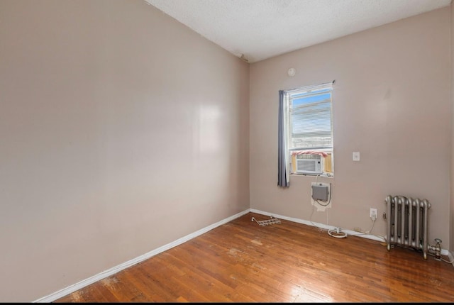 empty room featuring radiator, hardwood / wood-style floors, and a textured ceiling