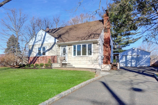 view of front of home with a front yard, a garage, and an outdoor structure