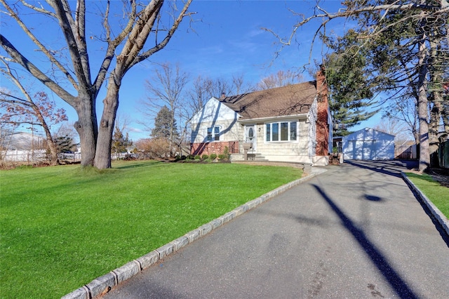 view of front facade with a front yard, a garage, and an outdoor structure