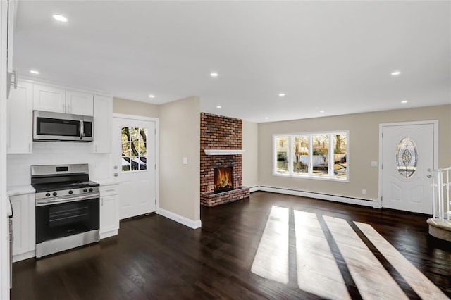 kitchen with stainless steel appliances, tasteful backsplash, a brick fireplace, white cabinetry, and a baseboard radiator