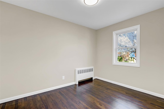 empty room with dark hardwood / wood-style flooring and radiator heating unit