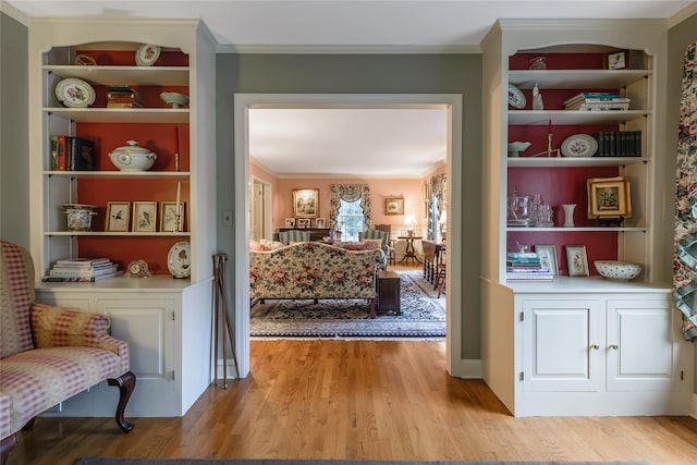 living area featuring ornamental molding, light hardwood / wood-style flooring, and built in features