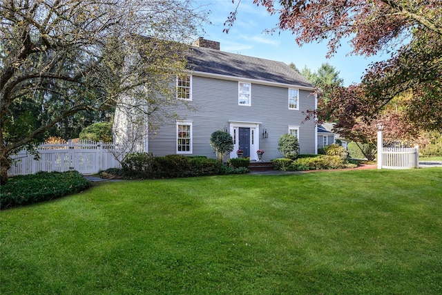 view of front of property with a chimney, a front yard, and fence