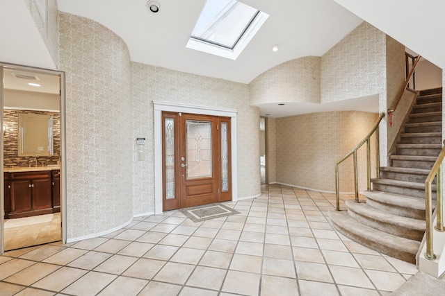 foyer entrance featuring lofted ceiling with skylight and light tile patterned flooring