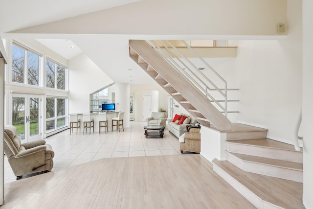 unfurnished living room with french doors, a towering ceiling, and light wood-type flooring