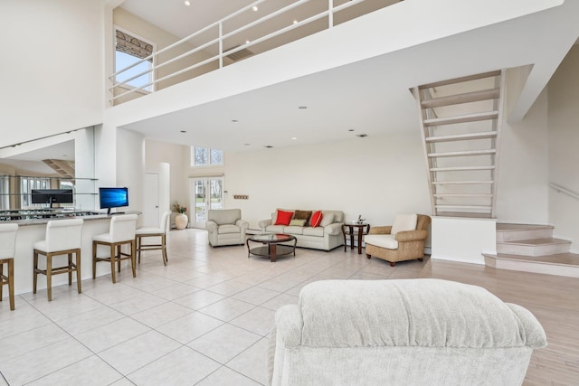 living room with a towering ceiling and light tile patterned floors