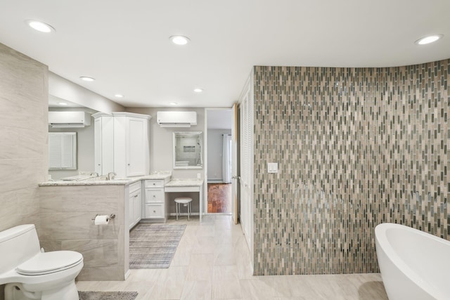 bathroom featuring vanity, an AC wall unit, a washtub, toilet, and tile walls