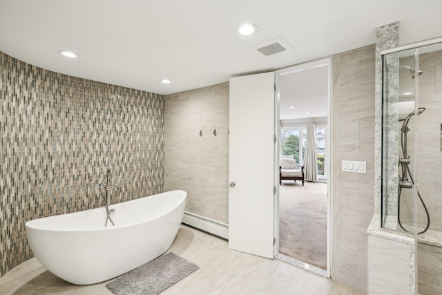 bathroom featuring shower with separate bathtub, baseboard heating, and tile walls