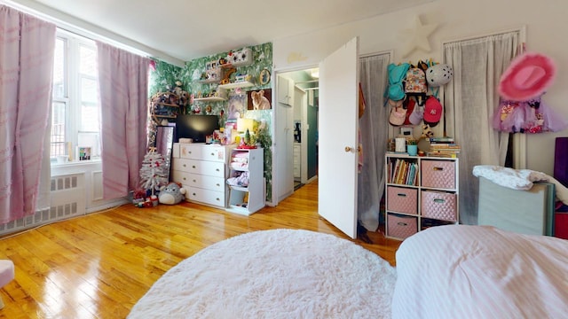 bedroom with wood-type flooring and radiator heating unit