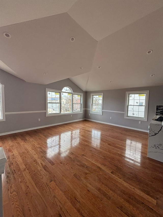 unfurnished living room with a healthy amount of sunlight, wood-type flooring, and lofted ceiling