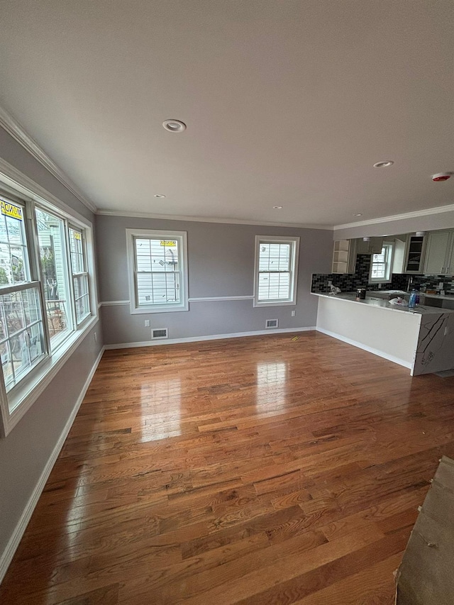 unfurnished living room with a healthy amount of sunlight, dark hardwood / wood-style floors, and crown molding