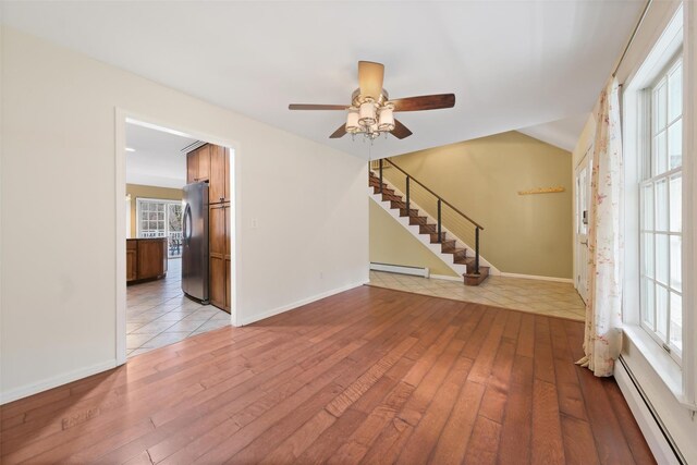 unfurnished room featuring ceiling fan, light wood-type flooring, and baseboard heating