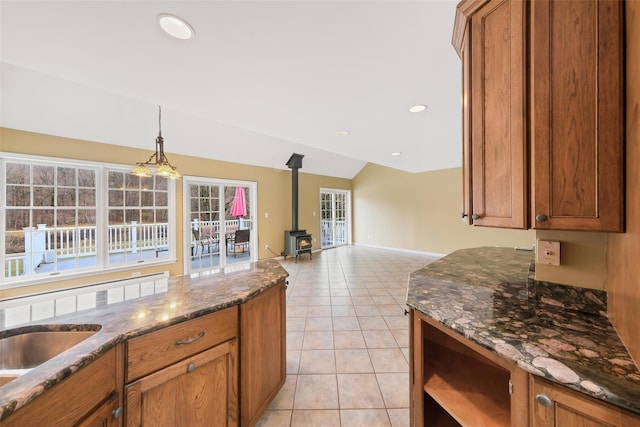 kitchen featuring a wood stove, plenty of natural light, light tile patterned flooring, and vaulted ceiling