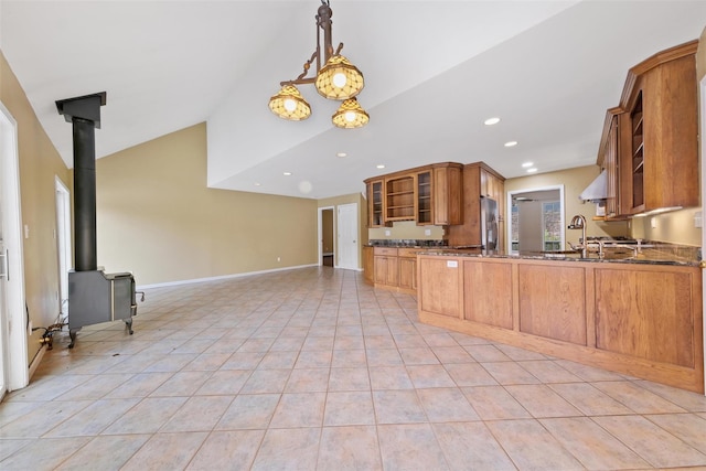 kitchen featuring pendant lighting, a wood stove, vaulted ceiling, light tile patterned floors, and kitchen peninsula