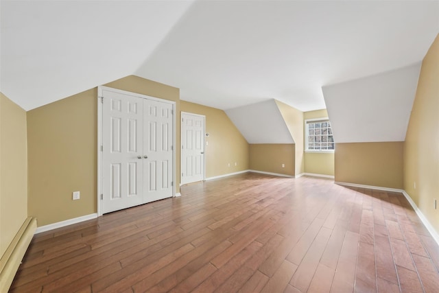 additional living space featuring wood-type flooring, baseboard heating, and lofted ceiling