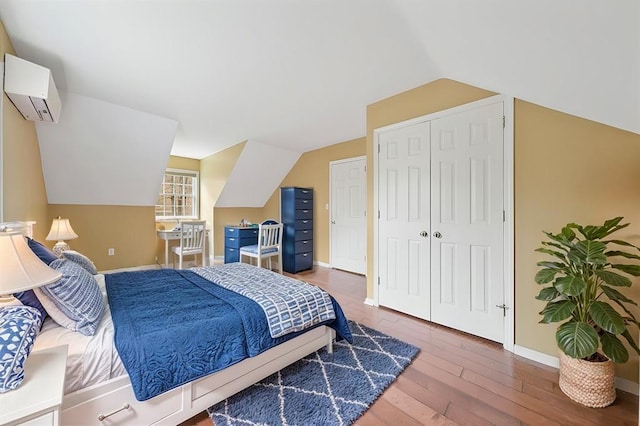 bedroom featuring wood-type flooring, an AC wall unit, and lofted ceiling