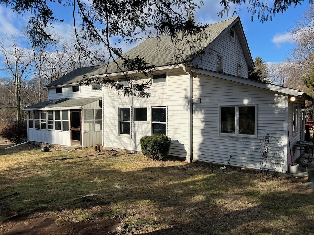 rear view of house featuring a lawn and a sunroom