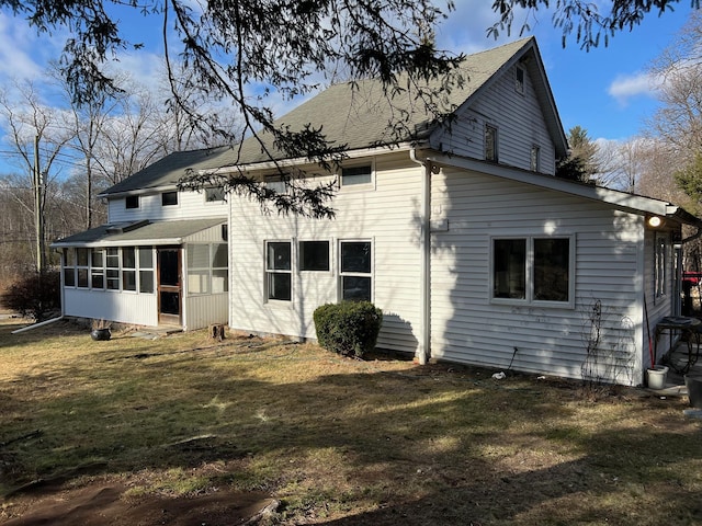 rear view of house featuring a lawn and a sunroom