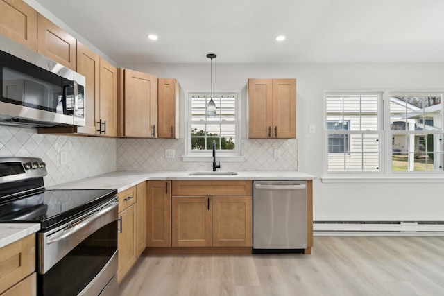 kitchen featuring sink, hanging light fixtures, stainless steel appliances, baseboard heating, and light hardwood / wood-style floors