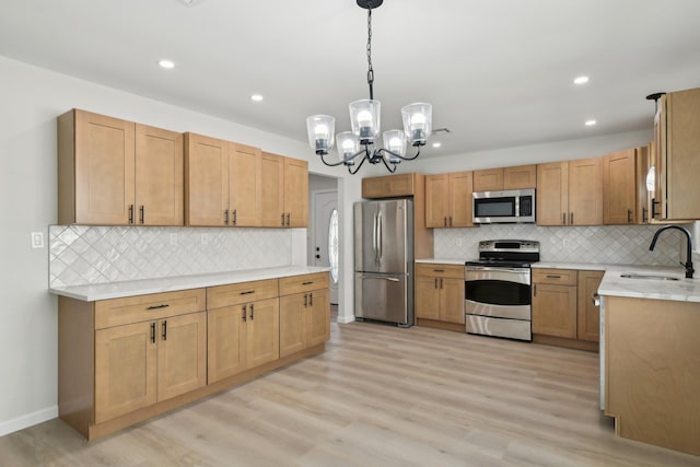 kitchen with stainless steel appliances, sink, an inviting chandelier, light hardwood / wood-style flooring, and hanging light fixtures