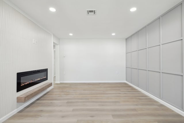 unfurnished living room featuring a large fireplace and light hardwood / wood-style floors