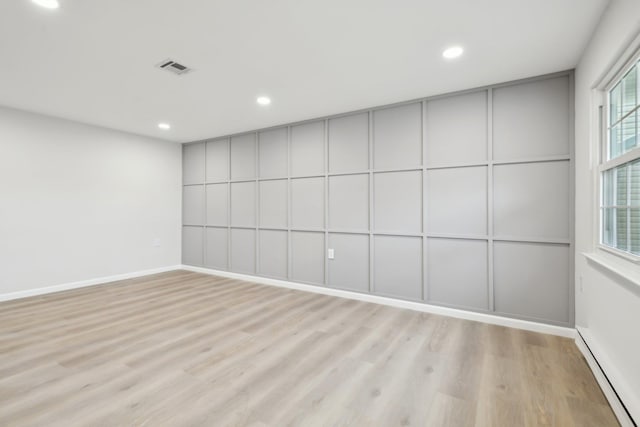 empty room with a baseboard radiator and light hardwood / wood-style floors