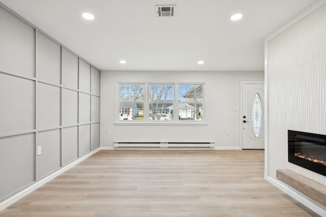 unfurnished living room featuring light hardwood / wood-style flooring, a fireplace, and a baseboard radiator