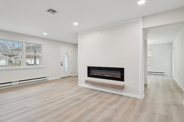 unfurnished living room featuring a fireplace, light wood-type flooring, and baseboard heating