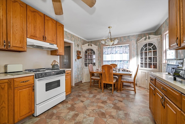 kitchen featuring pendant lighting, ceiling fan with notable chandelier, ornamental molding, and gas range gas stove