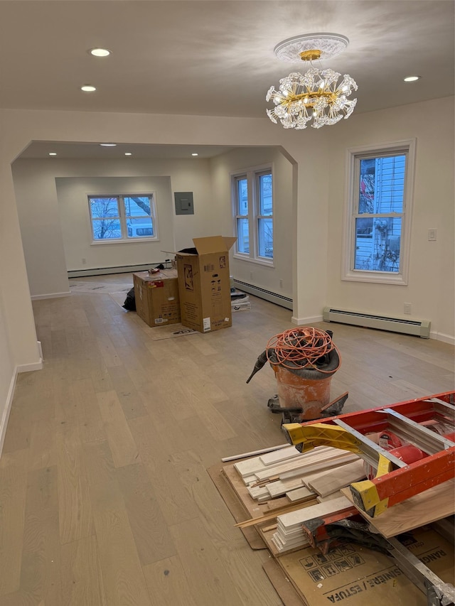 interior space with light wood-type flooring, baseboard heating, and a notable chandelier