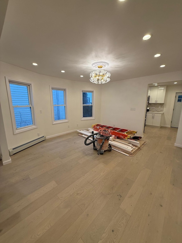 interior space with light hardwood / wood-style flooring, a chandelier, and a baseboard heating unit