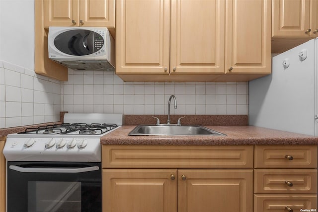 kitchen featuring light brown cabinetry, white appliances, tasteful backsplash, and sink